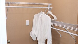 Et badeværelse med beige vægge, et hvidt håndklædestativ og en hvid badekåbe hængende på stativet.