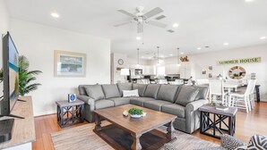 A modern living room with a sofa, coffee table, and a TV. - Hangloose Hideaway Beach House w/ a pool. 1 block to beach. Great fall rates! (Gulf Shores)