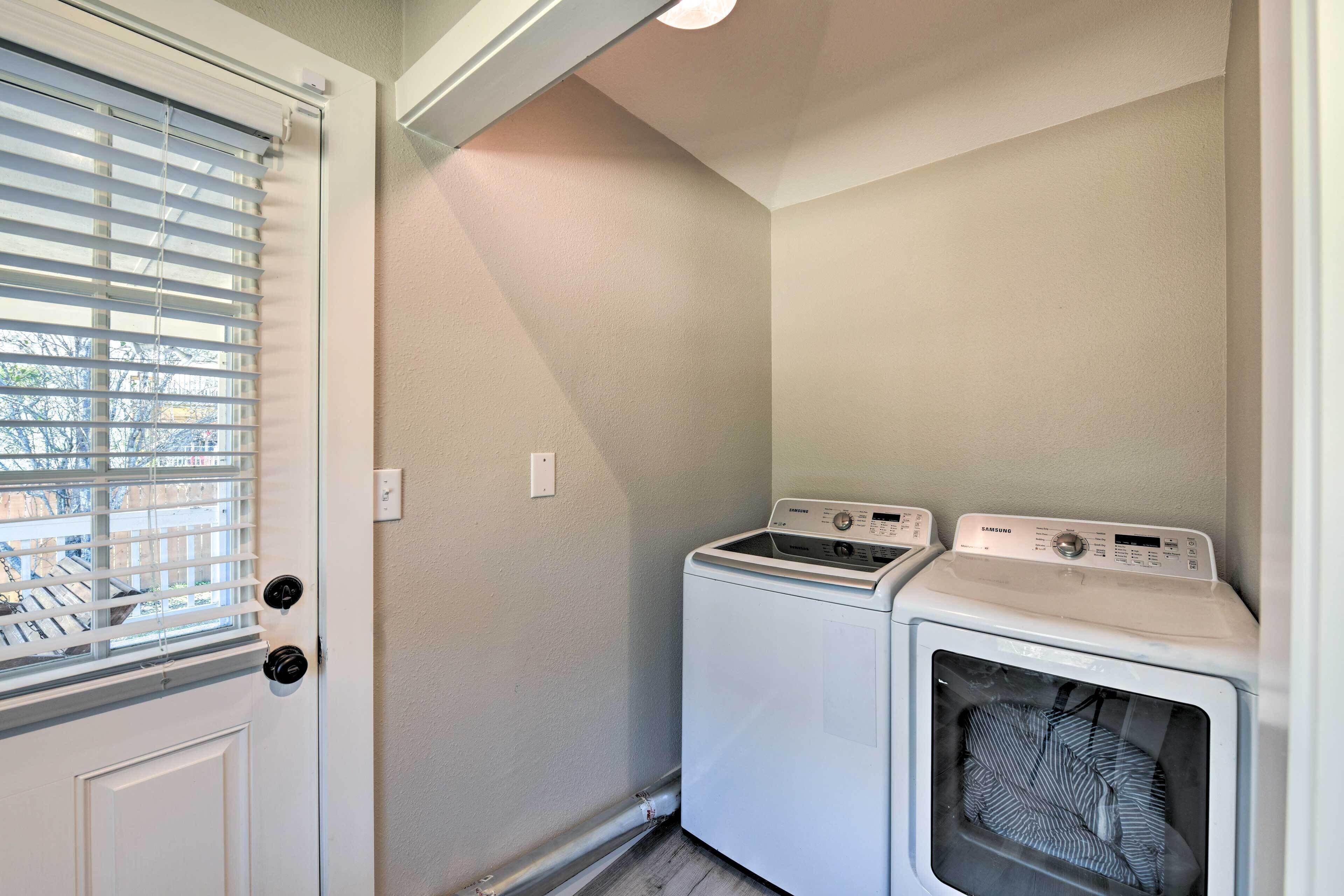 A laundry room with two washing machines, a door with a window, and a light switch on the wall.