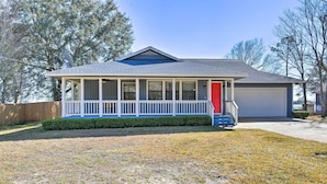 A single-story house with a covered porch, a garage, and a well-maintained lawn. - Updated Waterfront Escape w/ Dock & Fire Pit (Pensacola)