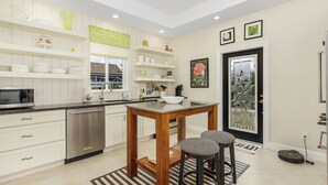 A modern kitchen with white cabinetry, a wooden dining table, and bar stools. - 2/2 Home in Bokeelia, Boat Lift Included! (Bokeelia)
