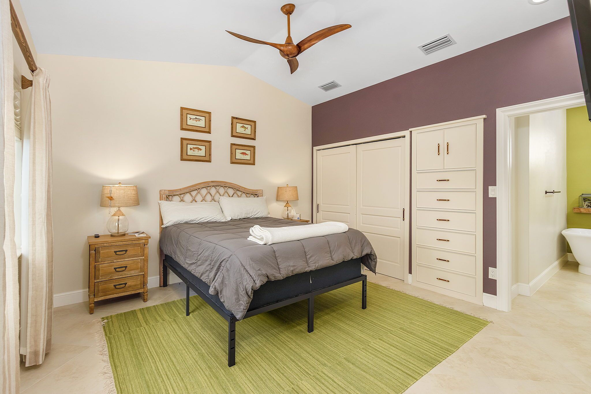 A bedroom with a bed, bedside tables, a ceiling fan, and a wardrobe.