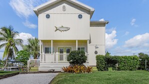 A two-story building with a large fish mural on the front wall, a covered porch, and a well-maintained lawn. - 2/2 Home in Bokeelia, Boat Lift Included! (Bokeelia)