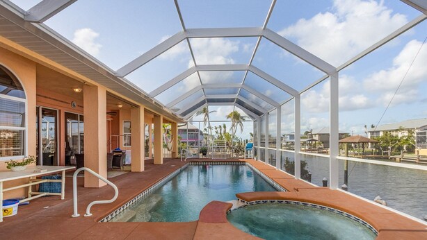 A pool area with a glass ceiling, a hot tub, and a view of the water. - 3/2 Beautiful Pool Home on the Water in St. James City! (Saint James City)