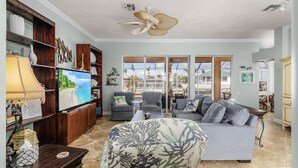 A spacious living room with a large TV, comfortable seating, and a ceiling fan. - 3/2 Beautiful Pool Home on the Water in St. James City! (Saint James City)
