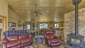 A cozy living room with a fireplace, leather sofas, a coffee table, and a ceiling fan.