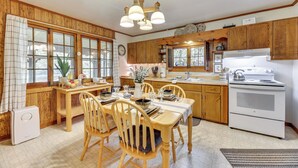 Une cuisine avec des meubles de rangement en bois, une cuisinière blanche et une table à manger avec des chaises.