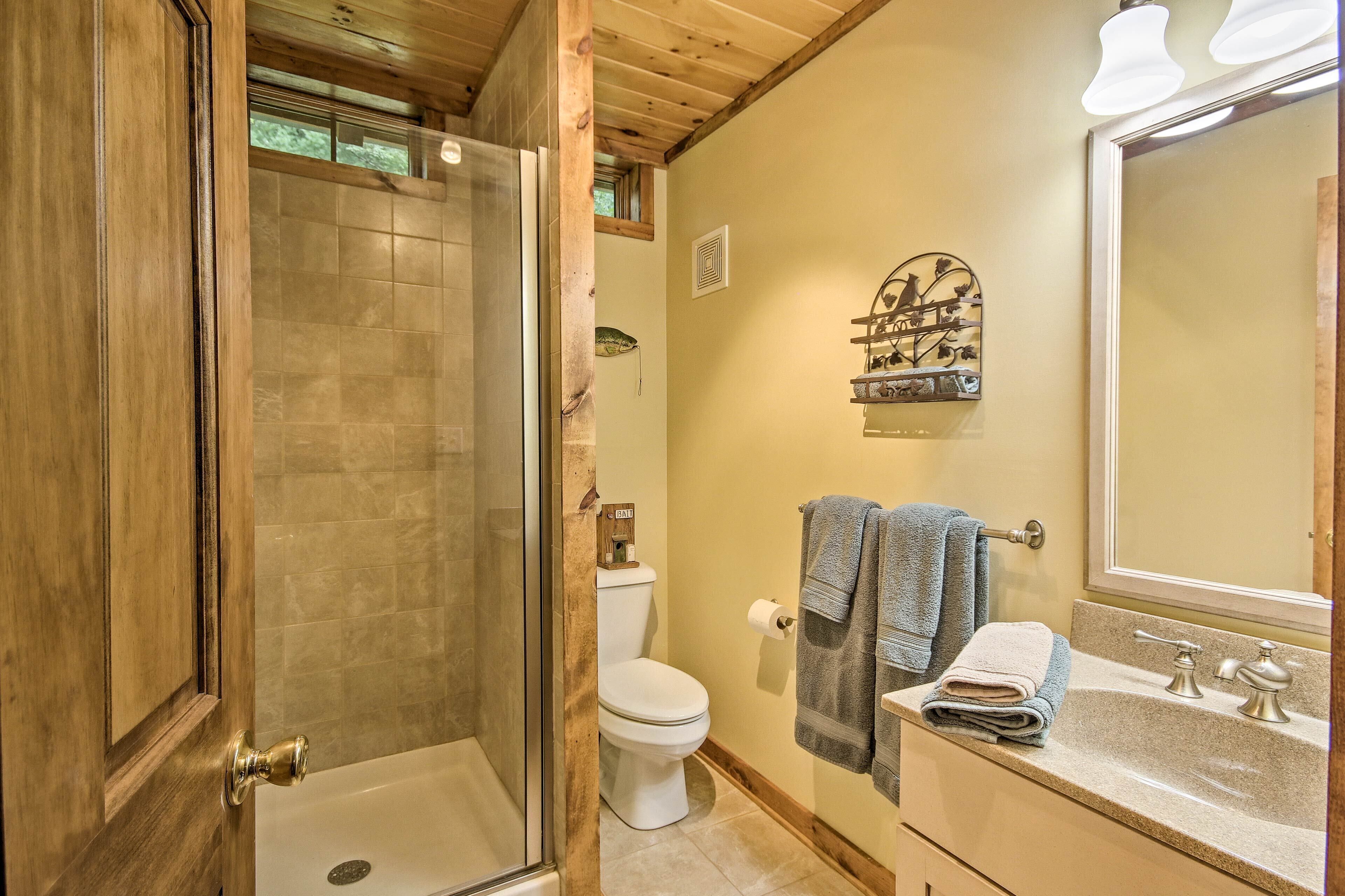 A bathroom with a shower, toilet, sink, and a towel rack.