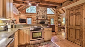 Una cocina amplia con armarios de madera, una chimenea de piedra y una isla grande con horno integrado.