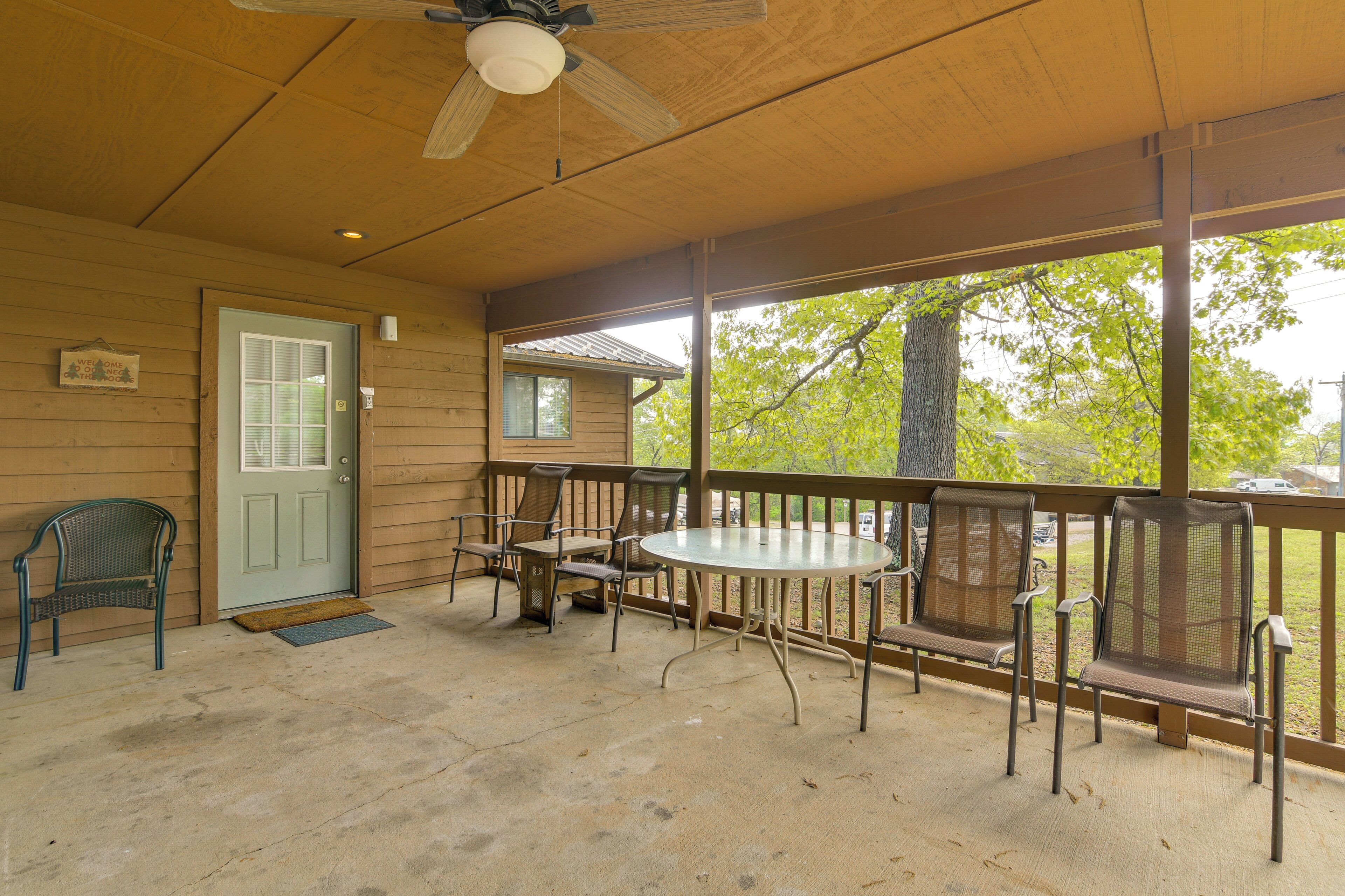 A covered porch with a table and chairs, a door, and a view of the outdoors.