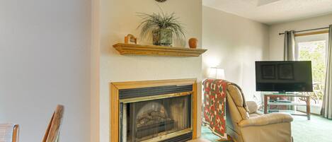 A living room with a fireplace, a television, and a comfortable chair.