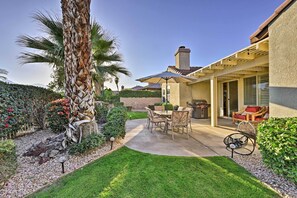 A patio with a table and chairs, a grill, and a covered seating area.