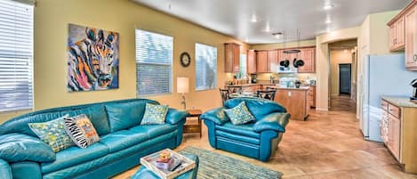 A spacious living room with a blue leather sofa set, a coffee table, and a large painting on the wall.