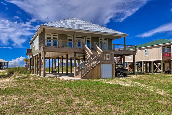 A two-story wooden house with a balcony, a covered porch, and a staircase leading to the upper level.