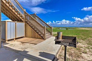 A wooden staircase leading to a covered deck area with a barbecue grill.