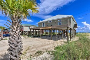 A beachfront house with a wooden deck and a balcony, surrounded by sand and vegetation. - Bayfront Dauphin Island Home w/ Beach Access! (Dauphin Island)