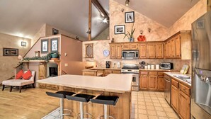 Eine Küche mit Holzausstattung, einer zentralen Kochinsel mit Barhocker, einer Mikrowelle, einem Herd und einem Kühlschrank.