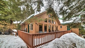 Eine Holzhütte mit einer Terrasse, umgeben von Schnee und Bäumen.