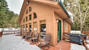 Eine Holzhütte mit einer Terrasse, Sitzgelegenheiten im Freien und einem Grill.