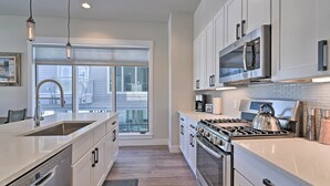 Una cocina moderna con electrodomésticos de acero inoxidable, un ventanal y vistas al exterior.