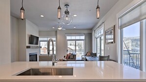Una cocina moderna con una isla grande, iluminación colgante y vistas al exterior.