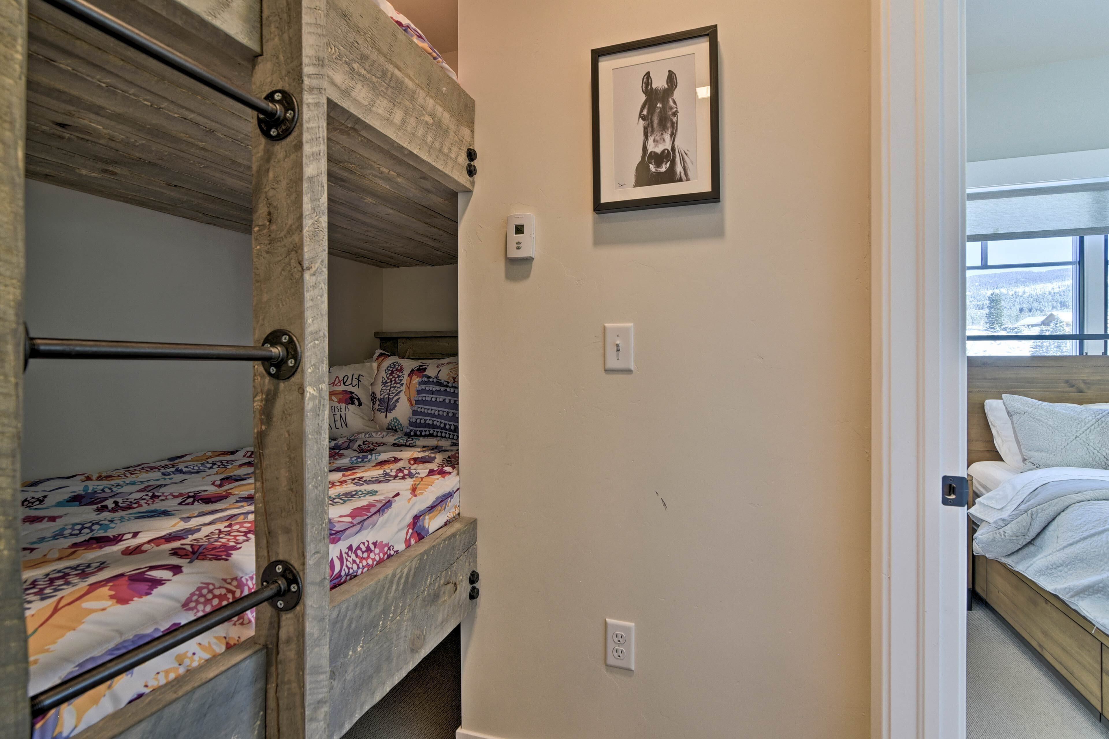 A bunk bed room with a framed horse picture on the wall, a thermostat, and a window with a view.