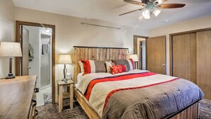 Une chambre à coucher avec un lit en bois, un ventilateur de plafond et une table de chevet avec une lampe.