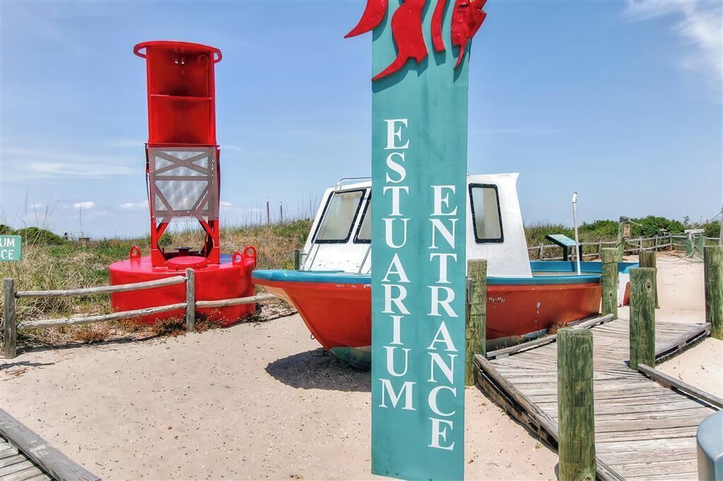 Placa indicando entrada na praia, com um barco atracado por perto.