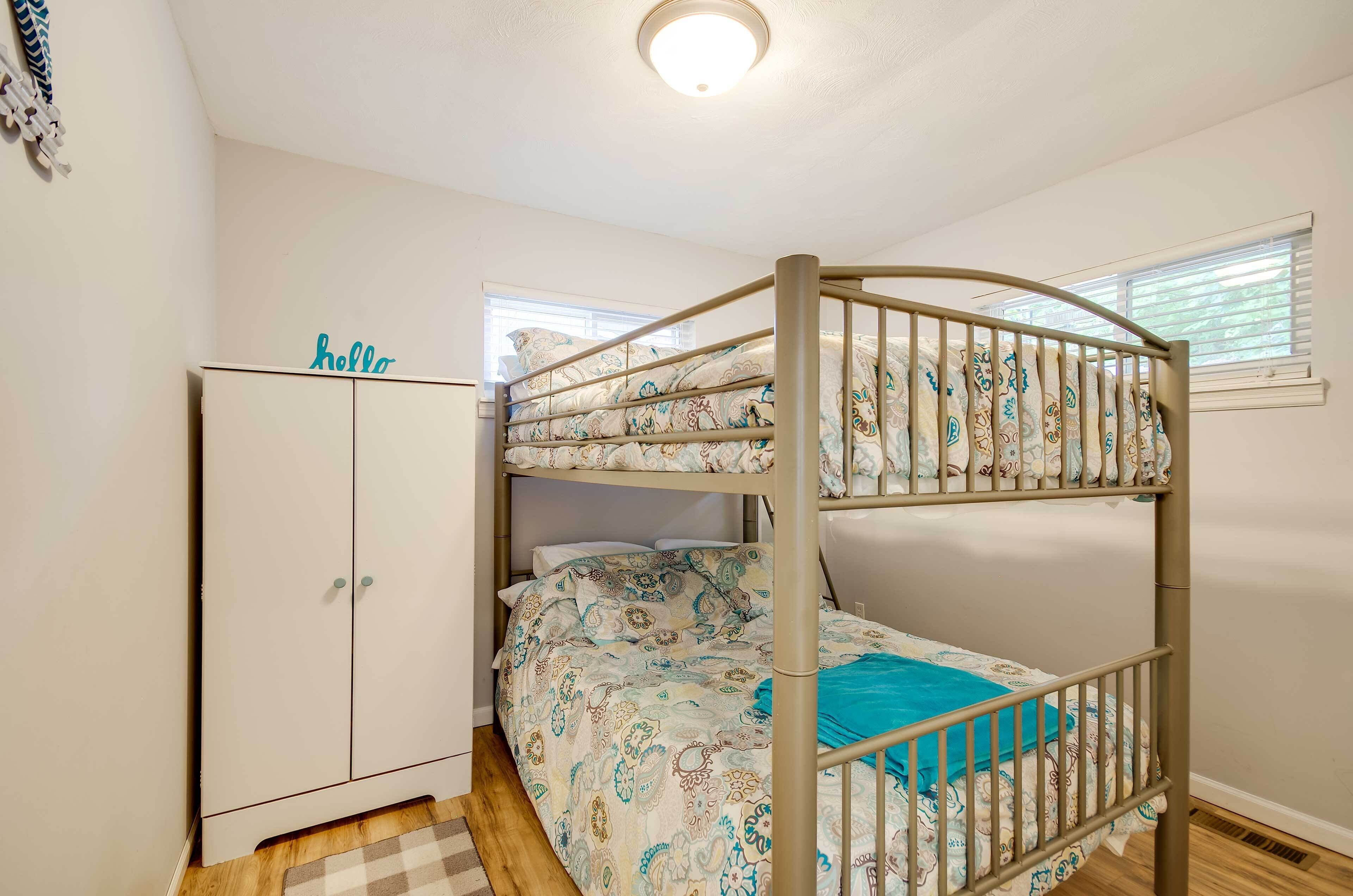 Een stapelbed met beddengoed met een patroon, een garderobe en een bordje met de tekst 'hello'.