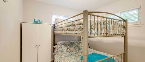 Een stapelbed met beddengoed met een patroon, een garderobe en een bordje met de tekst 'hello'.