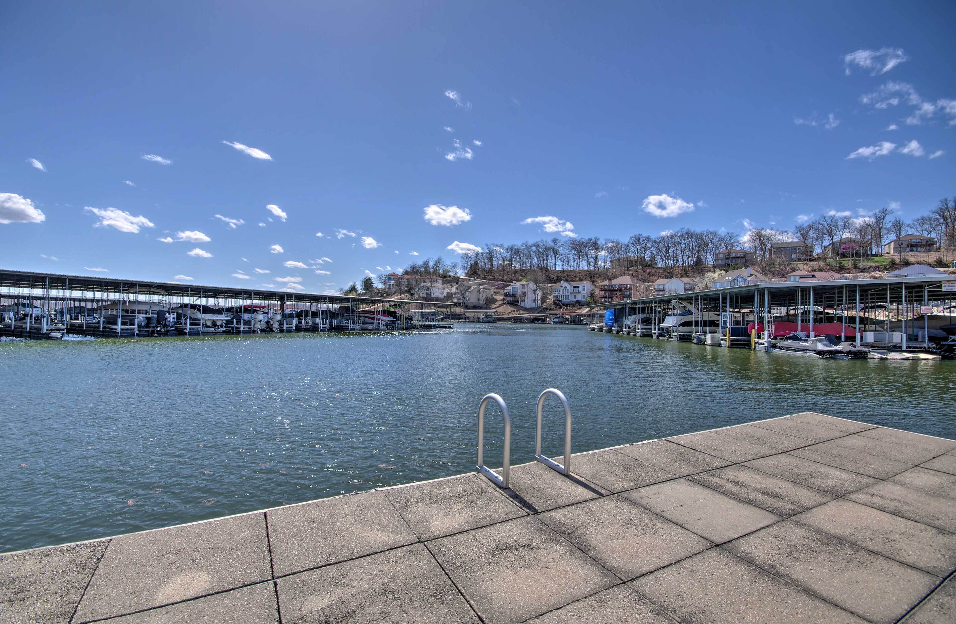 A waterfront swimming area with a dock, boats, and a covered seating area.