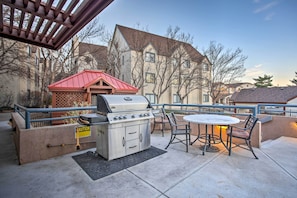 An outdoor patio with a grill, a table, and chairs. - Greenwood Village Condo w/ Pool Access! (Englewood)