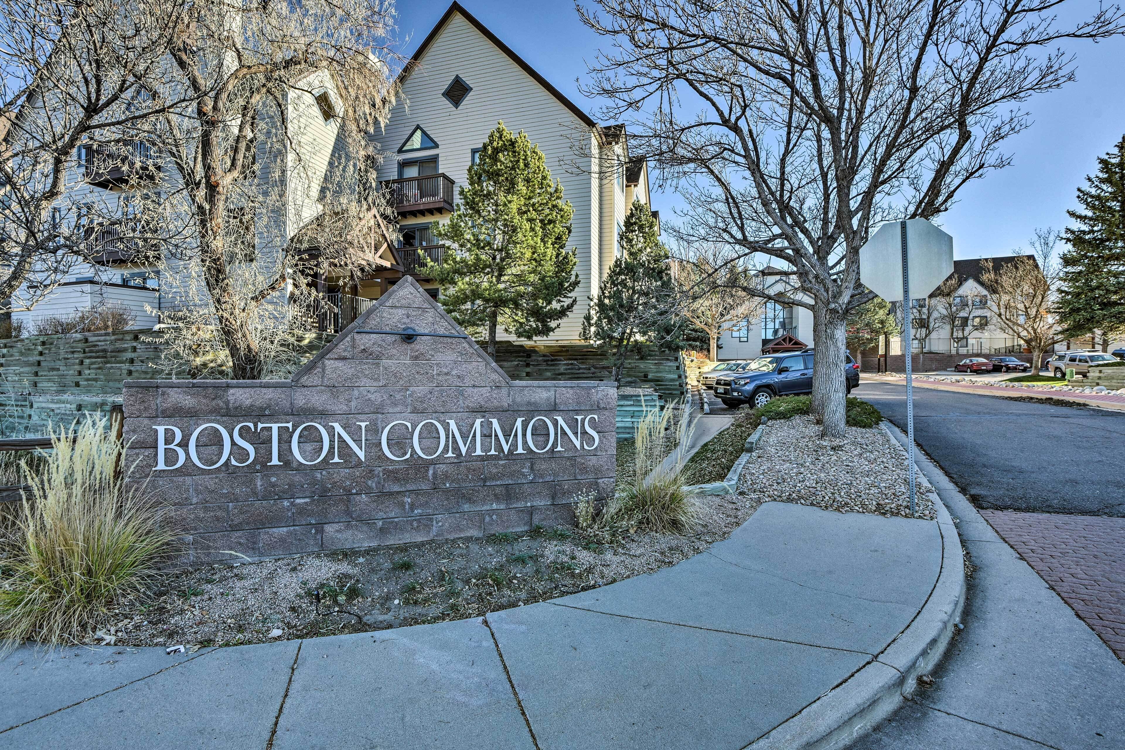A sign for 'BOSTON COMMONS' with a stone wall and a triangular stone structure in front.