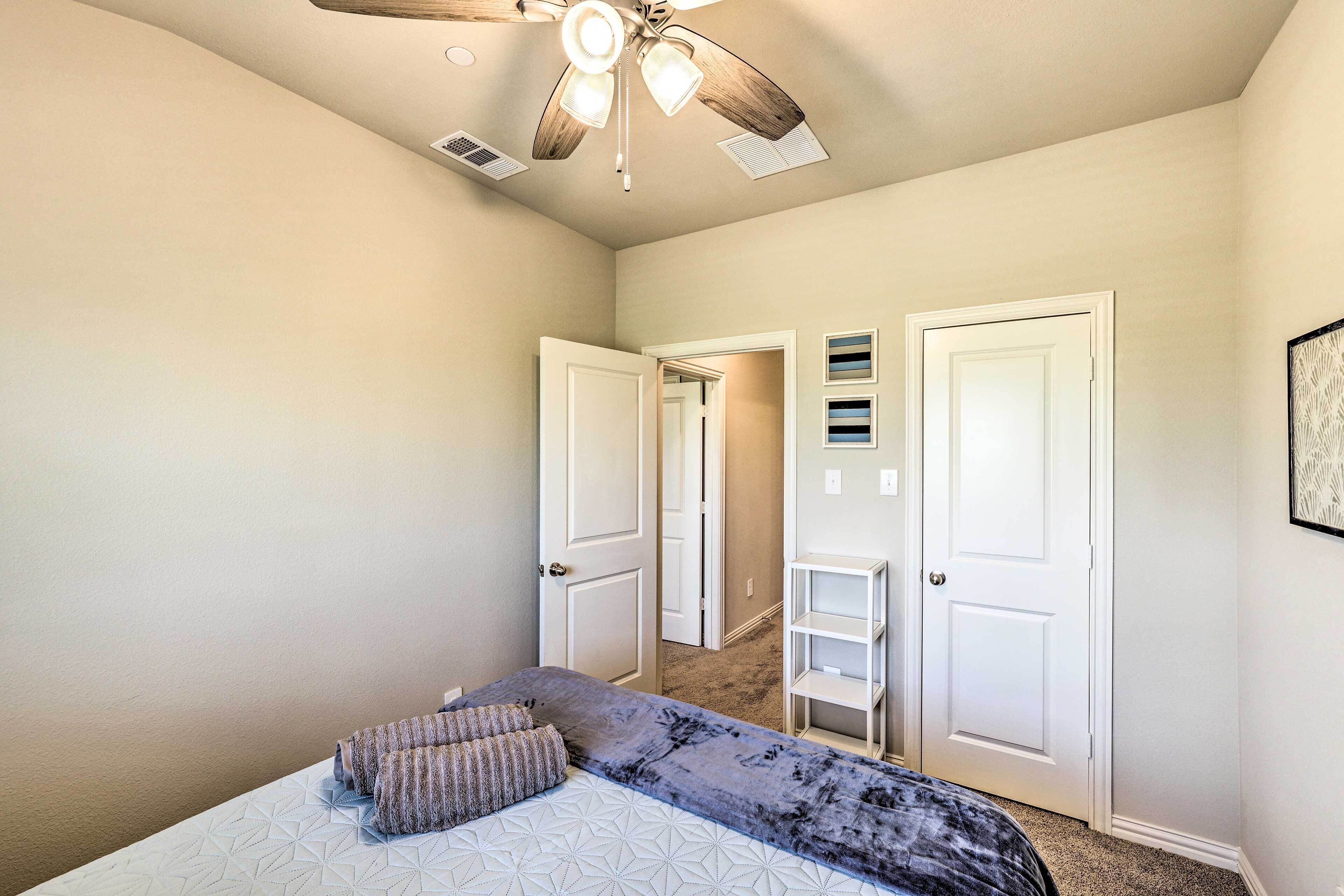 A bedroom with a bed, a ceiling fan, and two doors leading to other rooms.