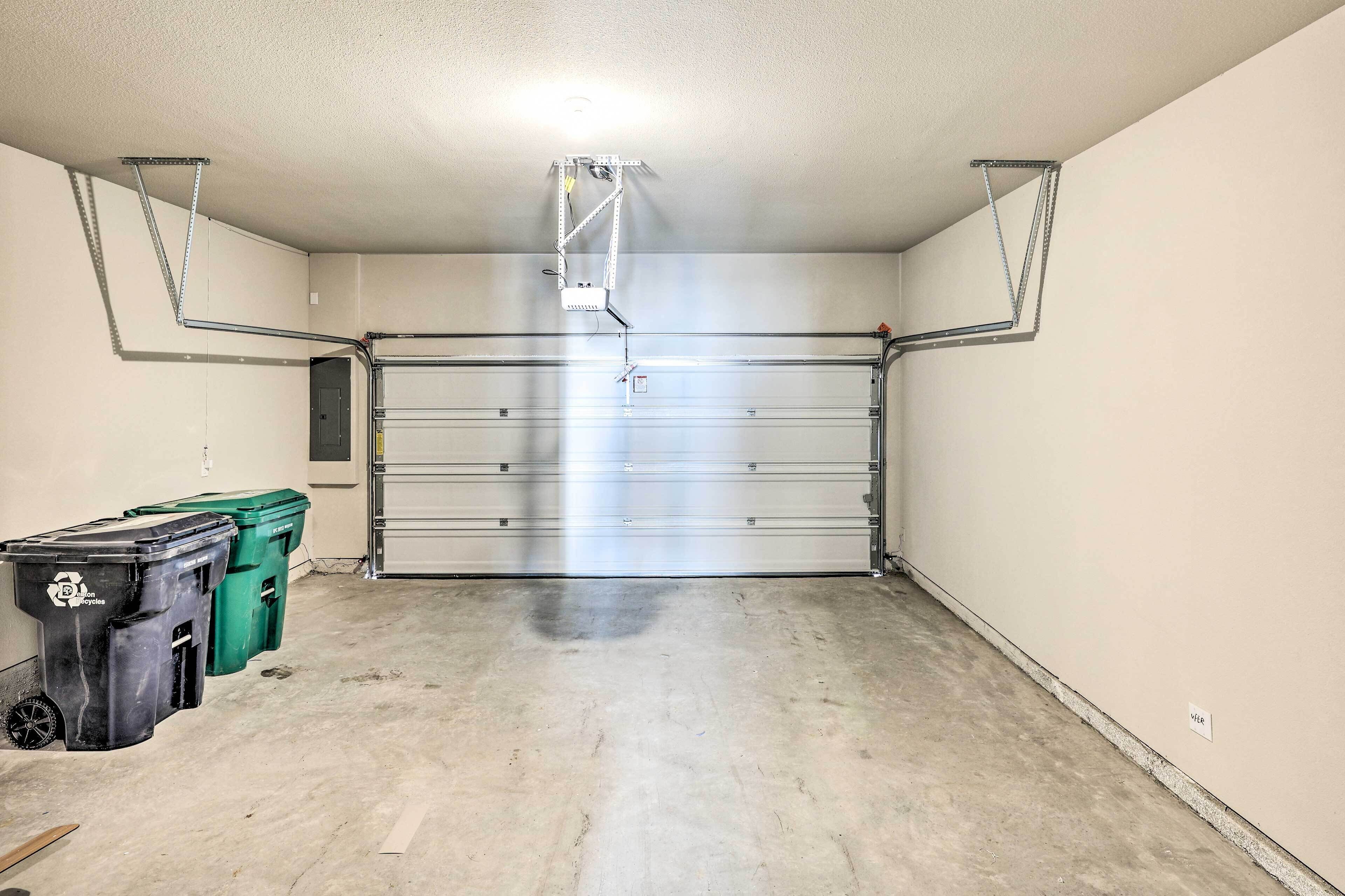 Eine Garage mit geschlossenem Garagentor, einer Deckenleuchte und zwei Mülltonnen auf der linken Seite.
