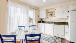 Una cocina moderna con armarios blancos, una mesa de comedor con sillas azules y una alfombra estampada en blanco y negro.