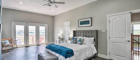 A spacious bedroom with a large bed, a ceiling fan, and a balcony with a view.