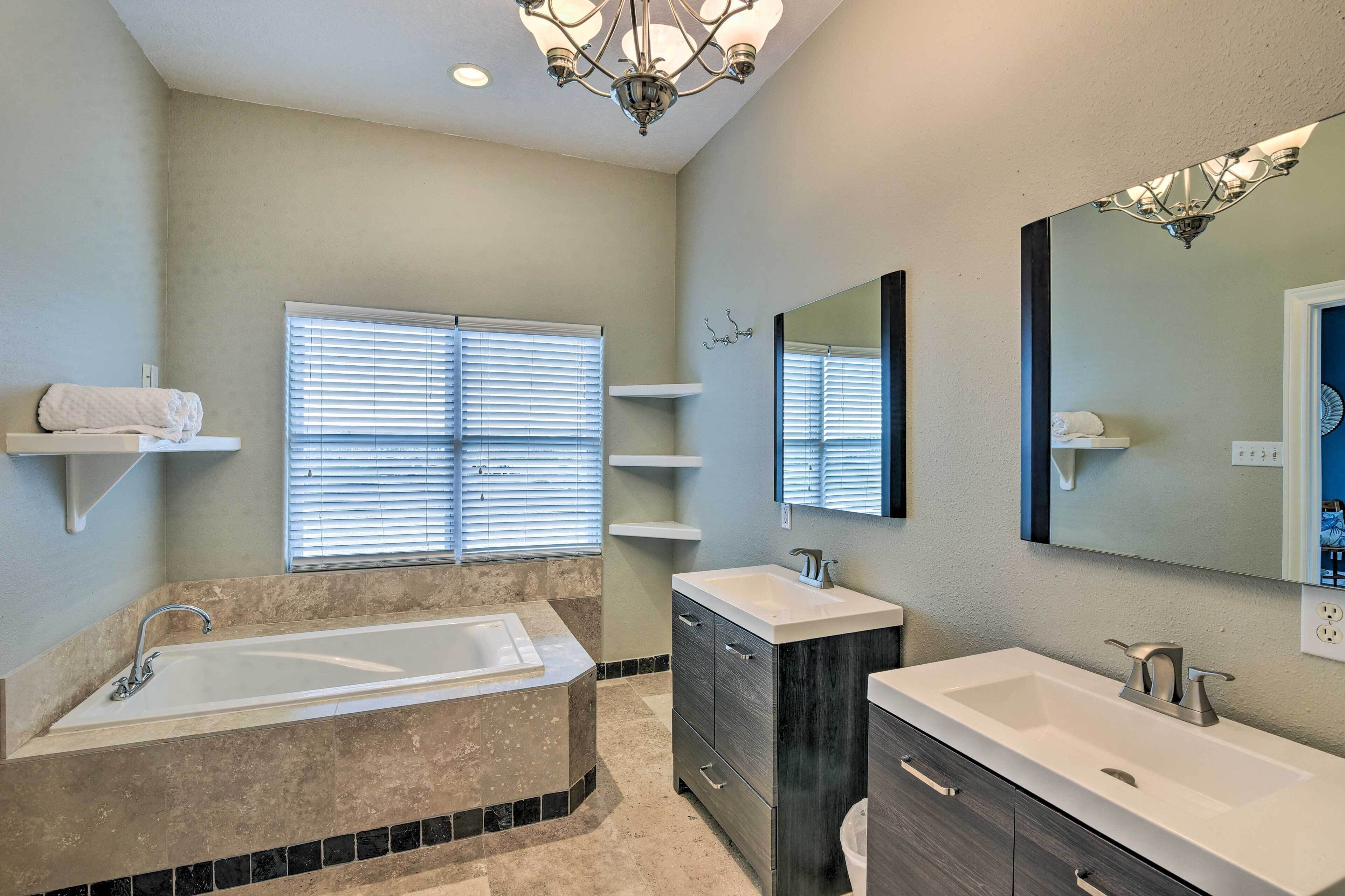 A modern bathroom with a freestanding bathtub, a vanity with a mirror, and built-in shelves.