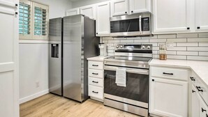 A modern kitchen with stainless steel appliances, white cabinetry, and a tiled backsplash. - 13 Mi to Dtwn Denver: Northglenn Townhome w/ Patio (Northglenn)