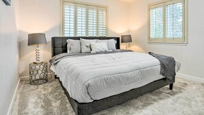 A bedroom with a large bed, two bedside tables, and two windows with shutters. - 13 Mi to Dtwn Denver: Northglenn Townhome w/ Patio (Northglenn)