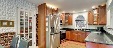 A modern kitchen with wooden cabinets, a stainless steel refrigerator, and a built-in oven.