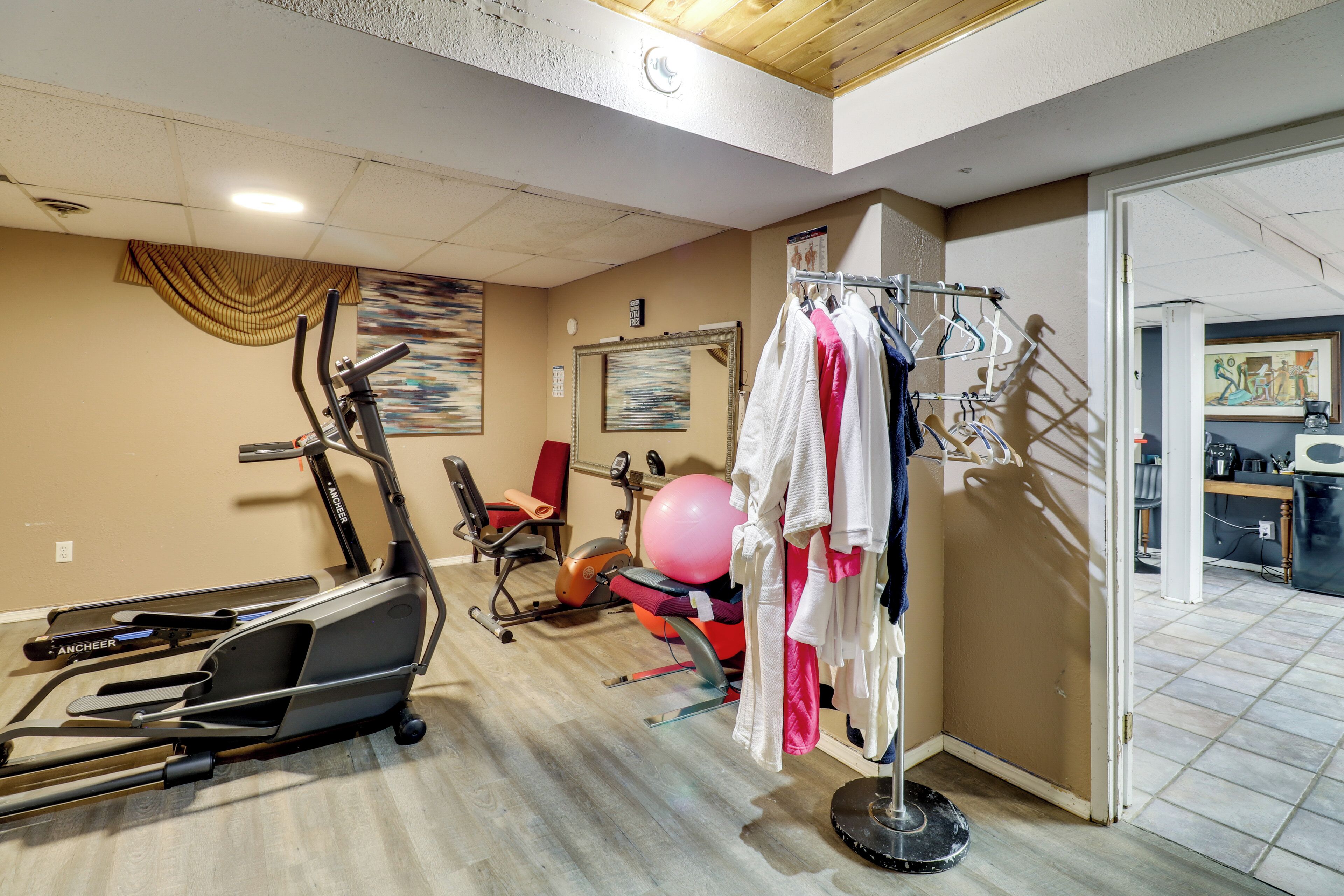 Une salle de sport à domicile équipée de matériel d’exercice, d’un portant à vêtements et d’un miroir.