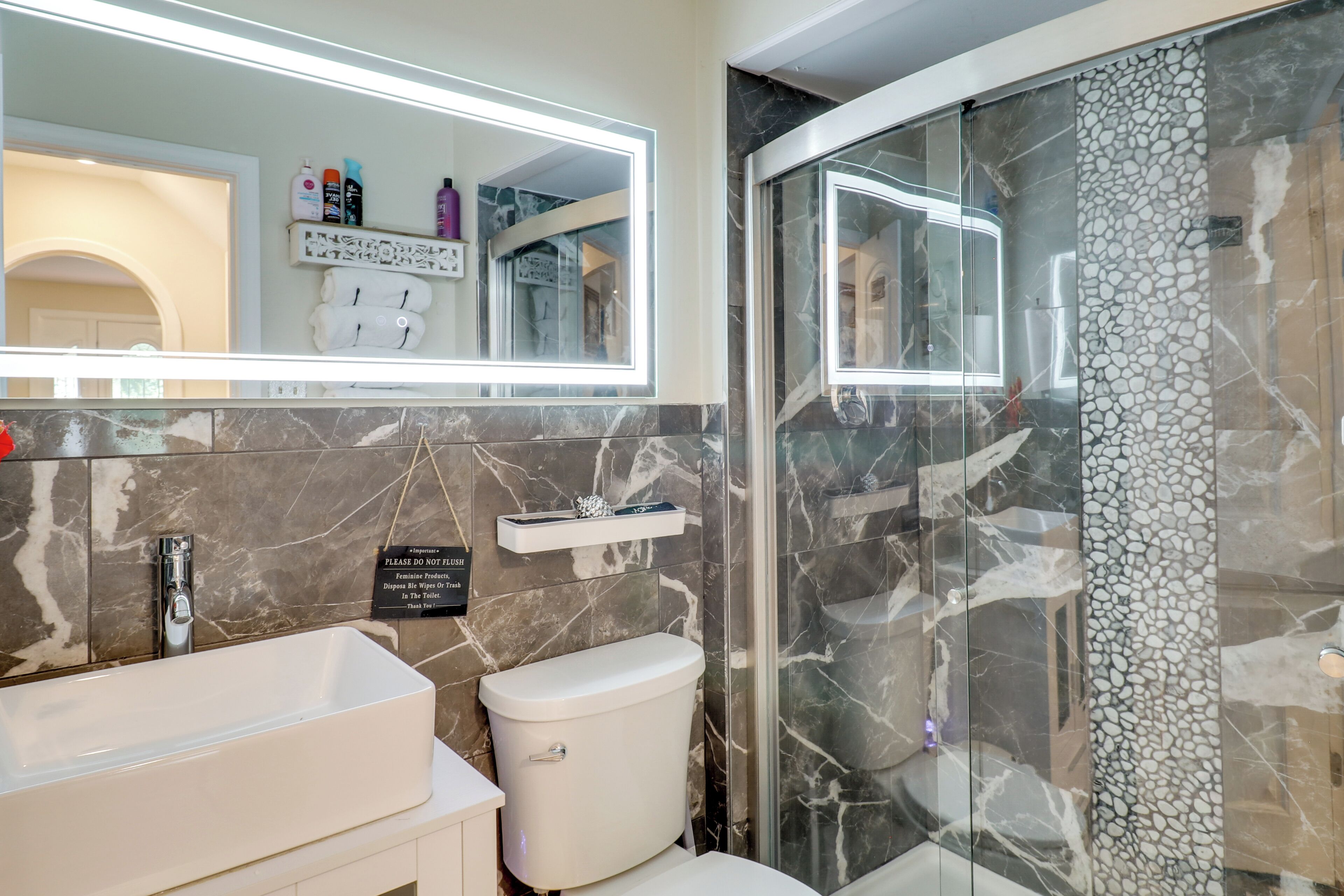 A bathroom with a vanity, toilet, and a glass-enclosed shower area.
