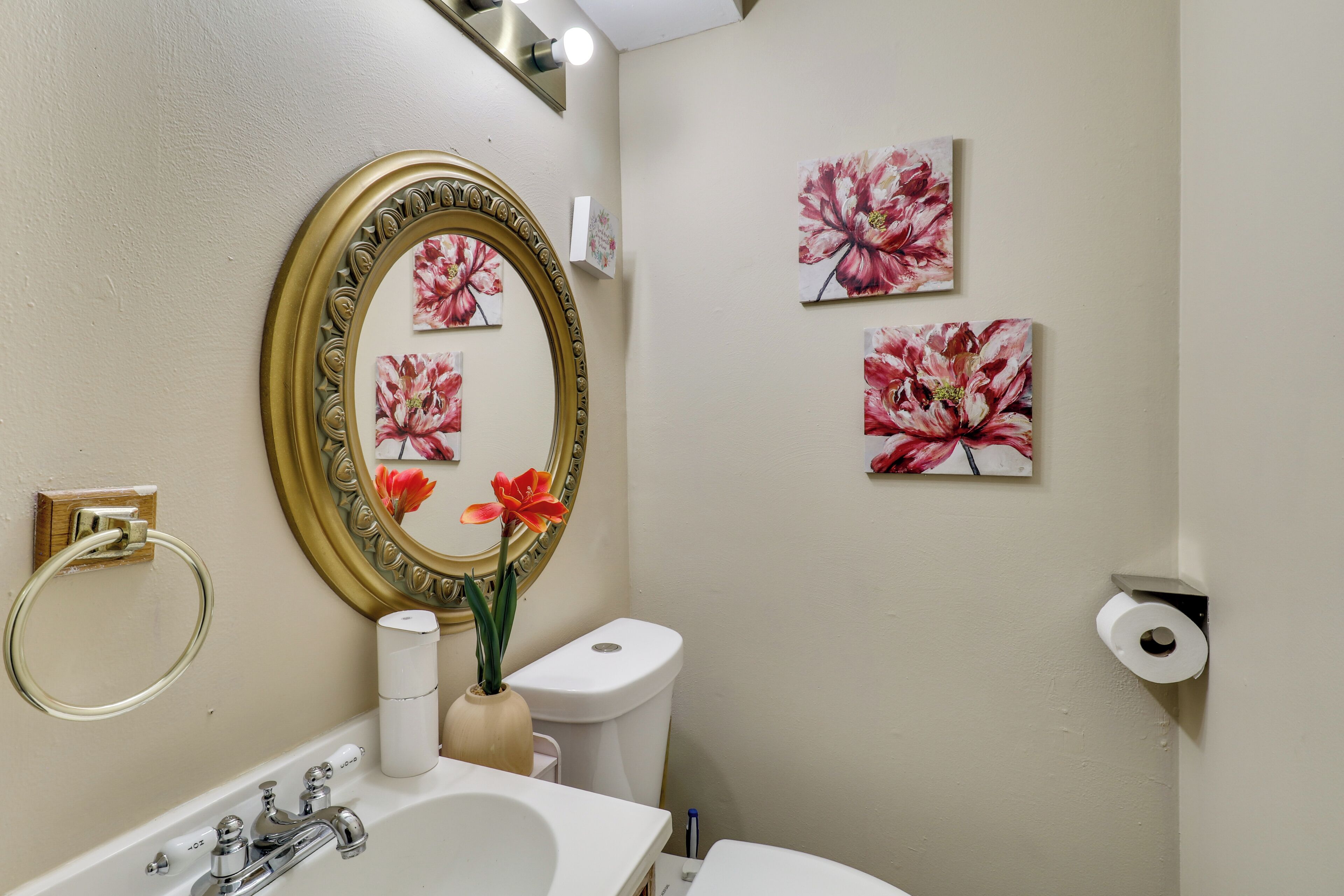 A bathroom with a sink, mirror, toilet, and toilet paper.