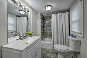 A modern bathroom with a vanity, sink, mirror, and a shower area. - Beautifully Renovated Beach House w/ Fenced Patio! (Atlantic City)