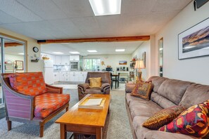 A living room with a sofa, armchair, and coffee table. There is a kitchen in the background. - Anchorage Apt: Home Base for Alaska Adventure! (Anchorage)