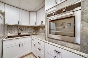 A modern kitchen with white cabinets, a stainless steel refrigerator, and a built-in oven. - Anchorage Apt: Home Base for Alaska Adventure! (Anchorage)
