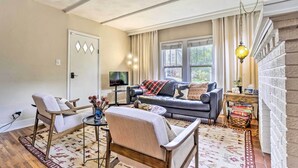 Een woonkamer met een bank, fauteuils, een televisie en een boekenkast.