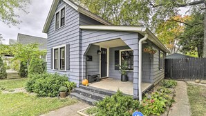 Een tweelaags huis met een veranda, een voortuin met een pompoen, en een blauw bordje dat naleving van ADA aanwijst.