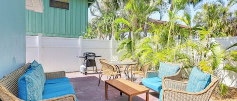 An outdoor patio with wicker furniture, a wooden table, and a grill.